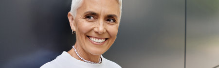 A mature woman with short hair beams with joy in her stylish outfit.