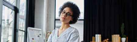 Appealing african american woman packing her items during lay off, colleagues on backdrop.の写真素材