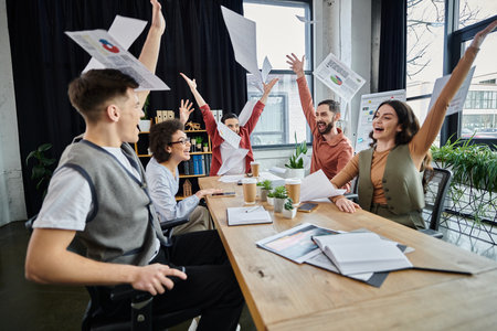 Team members express joy while navigating a challenging moment at work.の写真素材