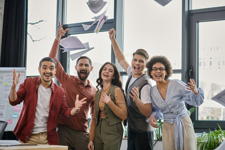 Team members joyfully embrace change while expressing hope in a bright office setting.の写真素材