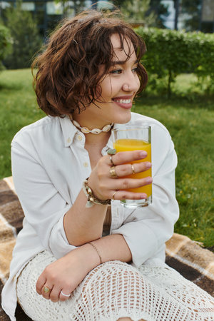A pretty young woman relaxes in a summer picnic, sipping a cool drink and enjoying the sunny weather.の写真素材