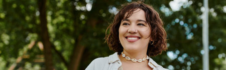 A young woman in a white shirt delights in a vibrant summer day surrounded by lush greenery.の写真素材