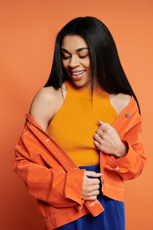 A woman smiles confidently while showcasing her trendy outfit.の写真素材