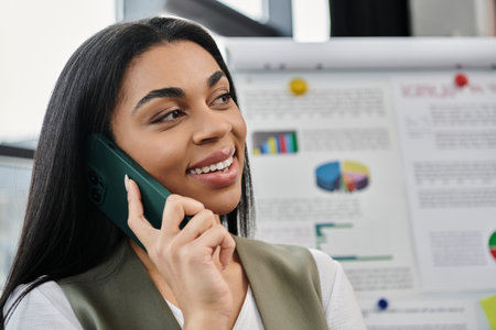 A confident woman smiles while talking on the phone, surrounded by vibrant charts.