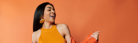 A woman radiates happiness while dancing in a bright orange setting.の写真素材