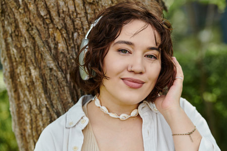 A young woman relaxes in a lush green park, listening to music and soaking in the summer sun.