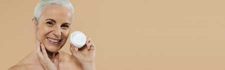 A mature woman happily holds jar of cream in hand.の写真素材