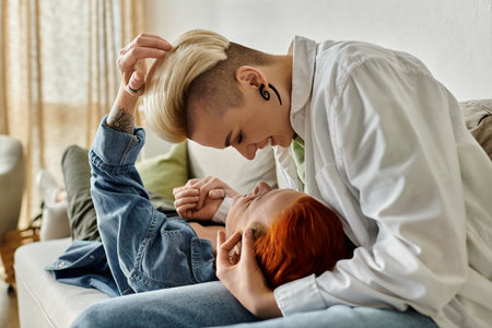 Two women with short hair sit on a cozy couch, wrapped in a loving hug, showcasing the beauty of connection.の写真素材