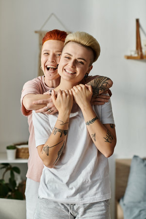 Two women with short hair sharing a heartfelt embrace in a cozy living room, expressing love and connection.の写真素材