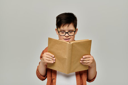 little child with Down syndrome with glasses reading intentlyの写真素材