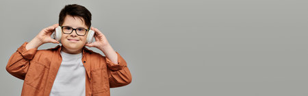 little child with Down syndrome with glasses covering ears with hands.の写真素材