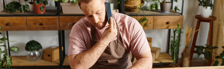 A man sits at a table, surrounded by plant pots in a small business setting.