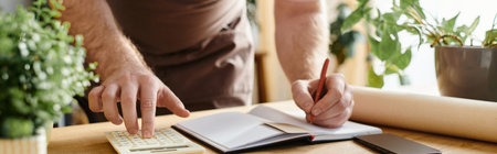 A man calculating on a desk in a plant shop, embodying the spirit of entrepreneurship and small business ownership.の写真素材