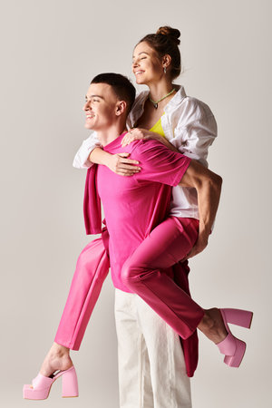 A man and a woman, dressed in pink, pose together in a studio with a grey background, showcasing their love and style.の写真素材