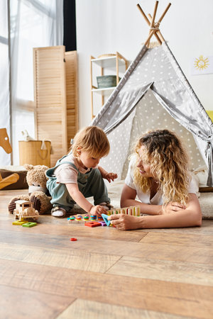 A curly-haired mother and her toddler daughter happily playing with toys on the floor, practicing the Montessori method of education.の写真素材