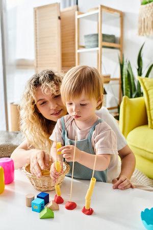 A curly mother and her toddler daughter are happily playing with toys, practicing the Montessori method of education at home.の写真素材