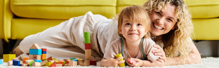 A woman with curly hair lays on the floor with her toddler daughter, engaging in the Montessori...