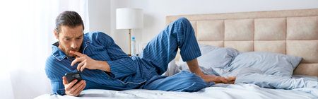 A man laying on a bed, engaged in a phone call.の写真素材