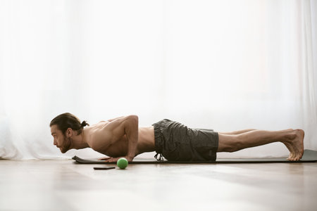 A man gracefully stretches at home.