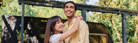 An interracial couple standing side by side, enjoying a romantic moment in the serene natural environment of their camper van getaway.の写真素材