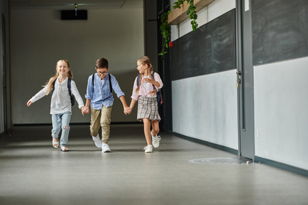A group of children, walking down a brightly lit hallway in a school.の写真素材