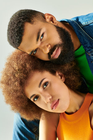 An African American man and woman, in colorful outfits, pose for a picture while sitting on a yellow...