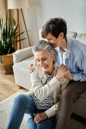 A heartwarming moment as two elderly women hug each other on the couch.の写真素材