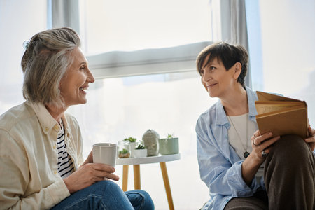 Two older women engaged in a lively conversation on a couch.の写真素材