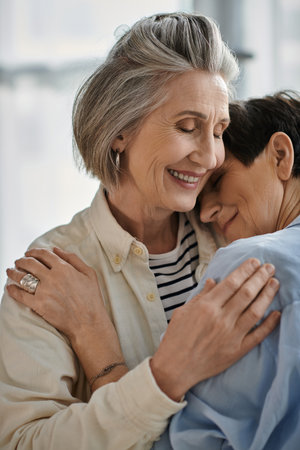 Two older women with loving expressions hugging each other tenderly.の写真素材