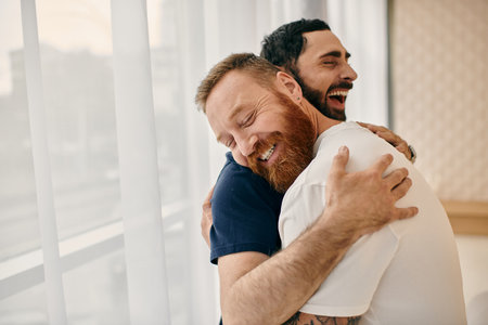 Two men in casual clothes embrace each other with love in a modern living room, captured in a tender moment by the window.の写真素材