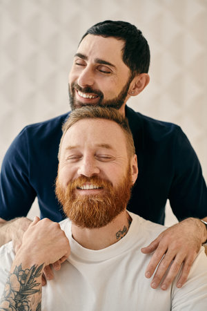 A happy gay couple, one with a red beard, sharing a warm hug in a cozy modern living room.の写真素材