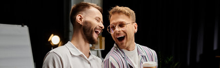 Two cheerful men collaboratively standing together in a workplace setting.