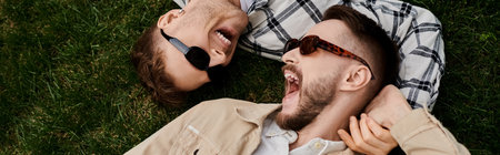 Two loving men enjoy a peaceful moment together, laying on the grass.