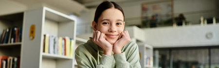 A teenage girl sits in a library, hands on her face, immersed in studying on a laptop after school.の写真素材
