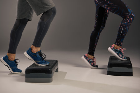 A young multicultural and fit couple wearing active attire balancing on a pair of steppers in a...