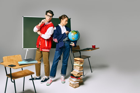 Two students standing at a desk, surrounded by books and a globe.