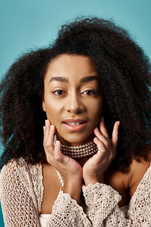 Stylish young woman with curly hairdo striking a pose on blue background.