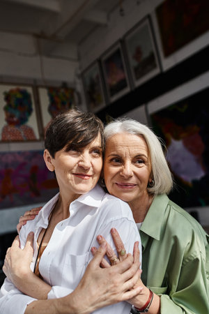 Two mature women hugging in an art studio.の写真素材