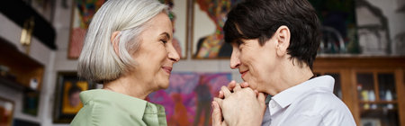 Mature lesbian couple stands together in art studio.の写真素材