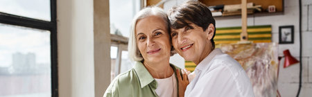 Mature lesbian couple standing together in an art studio.の写真素材