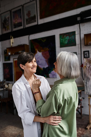 A woman hugs another woman in an art studio.の写真素材