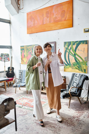 Mature lesbian couple standing in cozy art studio.の写真素材