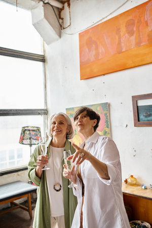 A mature lesbian couple standing together in an art studio.の写真素材
