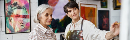Two women admire paintings in a gallery room.の写真素材