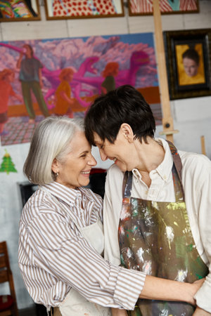 A mature lesbian couple standing in an art studio together.の写真素材