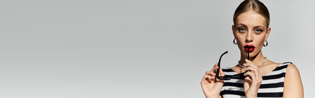 Stylish blonde woman in striped swimsuit striking a pose.の写真素材