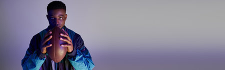 Handsome African American in trendy blue jacket holding a football.の写真素材