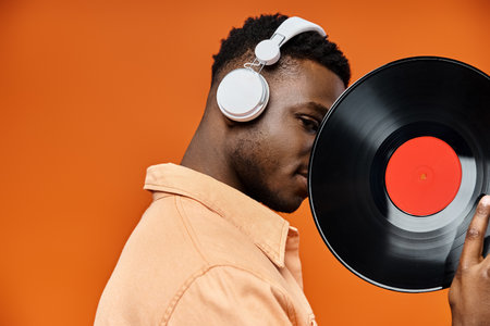 Stylish African American man with headphones holding vinyl record.