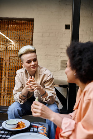 Two women engaged in a lively conversation at a cafe table.の写真素材