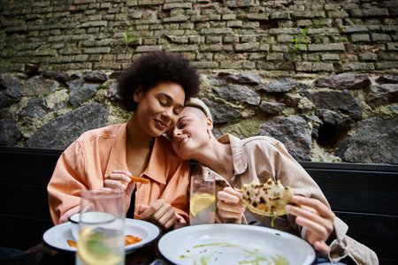 Diverse, beautiful couple of women sitting at a table, enjoying a meal together.の写真素材